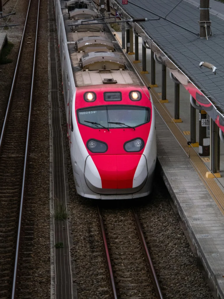 Aerial view of a red and white high-speed train arriving at Hsinchu Station, Taiwan.
