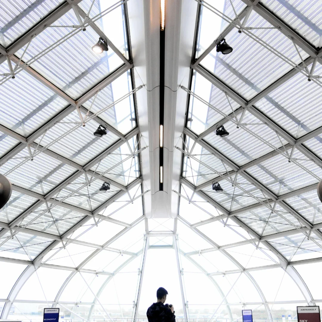 Futuristic glass-paneled architecture in an urban indoor setting with a lone figure.