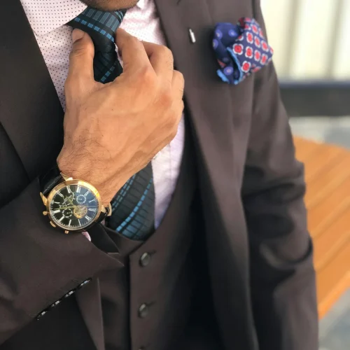 Elegant close-up of a man in a designer suit adjusting his tie, showcasing luxury fashion.