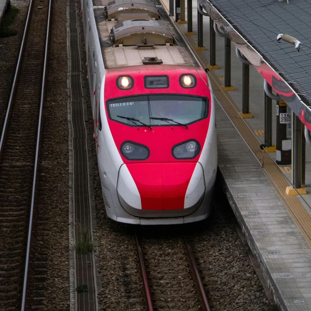 Aerial view of a red and white high-speed train arriving at Hsinchu Station, Taiwan.